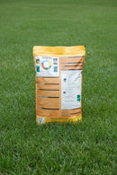 Back view of a fertilizer packaging with text and graphics on a wooden surface